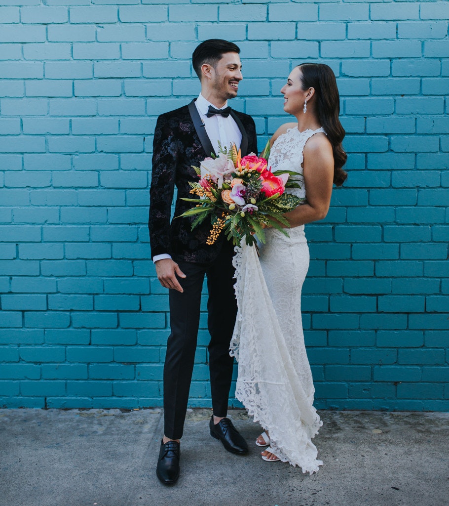 Wedding couple in front of a painted blue wall.